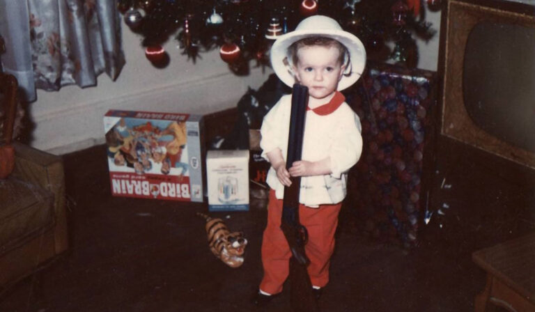 Desiree as a child holding a toy rifle
